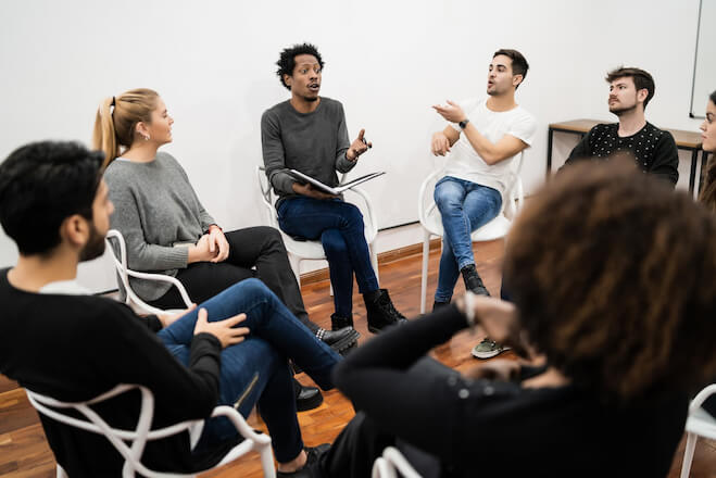 A group of diverse people sitting around in a circle talking.